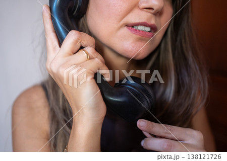 Young Woman Talking on Landline Phone at Home Near Wooden Door Young Woman Talking on Landline Phone at Home Near Wooden Door 138121726