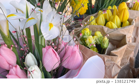 Beautiful bouquets of pink tulips and white irises in craft paper at a sunlit spring flower market Beautiful bouquets of pink tulips and white irises in craft paper at a sunlit spring flower market 138121749