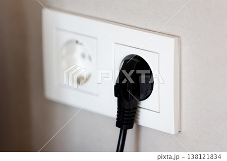 Black power plug connected to white wall socket Black power plug connected to white wall socket 138121834