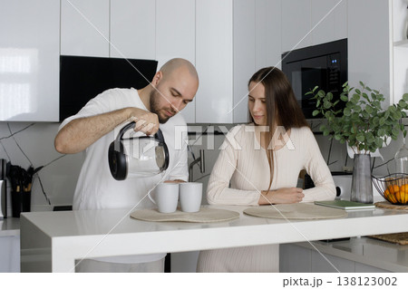 Nice woman and man enjoying a cup of drink in the morning together at home in their kitchen.  138123002