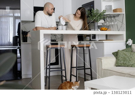 Romantic woman and man enjoying a cup of drink in the morning together at home in their kitchen.  138123011
