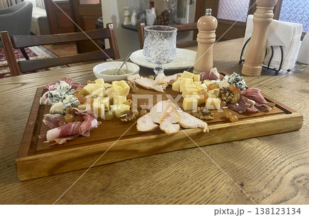a wooden cutting board with cheese and meat on it. italian antip 138123134