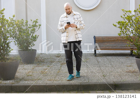 Young man walking and talking on phone outdoors 138123141