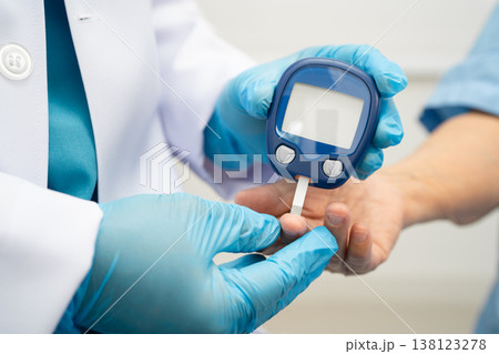 Asian doctor using digital glucose meter for check sample blood sugar level to treatment diabetes. Asian doctor using digital glucose meter for check sample blood sugar level to treatment diabetes. 138123278