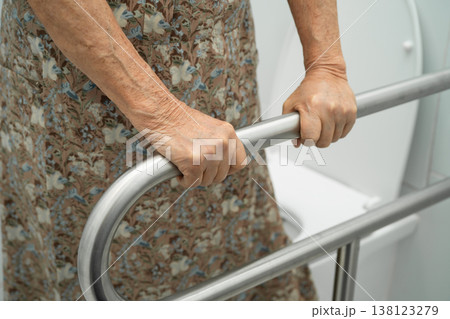 Asian elderly woman patient use toilet support rail in bathroom. Asian elderly woman patient use toilet support rail in bathroom. 138123279