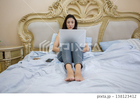 Attractive brunette woman using laptop and resting in comfortable hotel room indoor Attractive brunette woman using laptop and resting in comfortable hotel room indoor 138123412