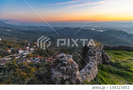 Rural countryside Albania. Mountain range with small village in the valley with sunset vibrant sky Rural countryside Albania. Mountain range with small village in the valley with sunset vibrant sky 138123852