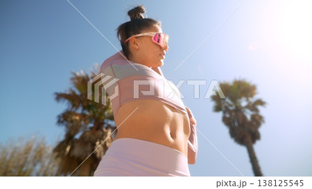 Fitness enthusiast engaging in dynamic warmup near palm trees 138125545