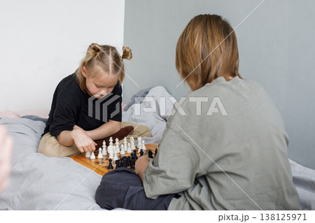 Thinking little girl and young boy have a nice game. Sibling playing chess  138125971