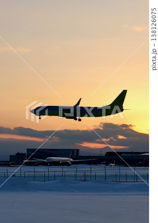 夕焼けをバックに着陸する機影「冬の新千歳空港」 夕焼けをバックに着陸する機影「冬の新千歳空港」 138126075