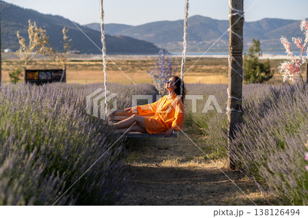 Relaxing on a Swing Surrounded by Blooming Lavender Fields in a Serene Landscape During the Afternoon 138126494