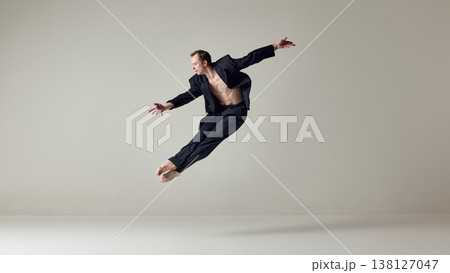 Male dancer captured in horizontal flight pose with extended body line in studio. Male dancer captured in horizontal flight pose with extended body line in studio. 138127047