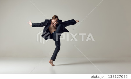 Male dancer executing powerful high kick with dynamic upper body motion in studio. 138127053