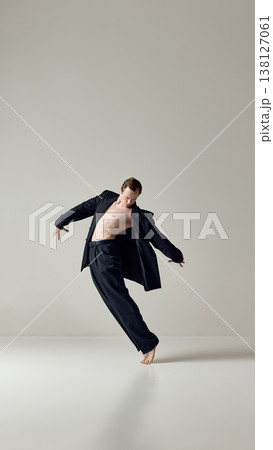 Male dancer balancing barefoot in loose suit during expressive movement Male dancer balancing barefoot in loose suit during expressive movement 138127061