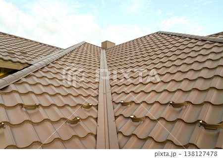 House roof surface covered with brown metal tile sheets. House roof surface covered with brown metal tile sheets. 138127478