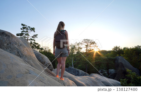 Hiker woman walking on mountain footpath enjoying evening nature. Lonely female traveler traversing wilderness trail. Healthy lifestyle concept Hiker woman walking on mountain footpath enjoying evening nature. Lonely female traveler traversing wilderness trail. Healthy lifestyle concept 138127480