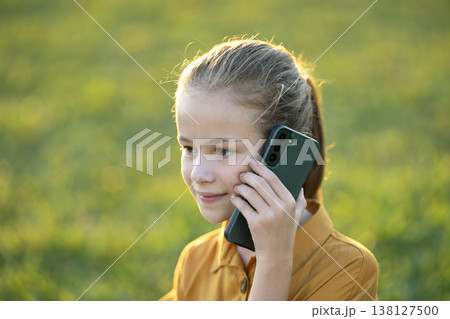 Happy pretty child girl talking on her cellphone in summer park 138127500