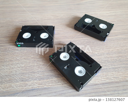 Three small digital video cassettes in MiniDV format on a wooden background. Retro media for video cameras Three small digital video cassettes in MiniDV format on a wooden background. Retro media for video cameras 138127607