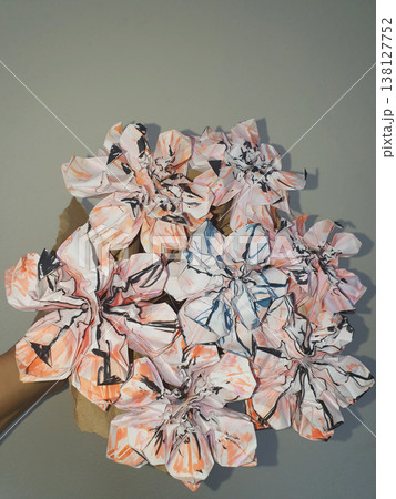 Hand holding a creative bouquet of origami paper flowers with abstract orange and black patterns 138127752