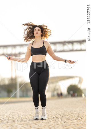 Woman exercising outdoors doing jump rope workout Woman exercising outdoors doing jump rope workout 138127768