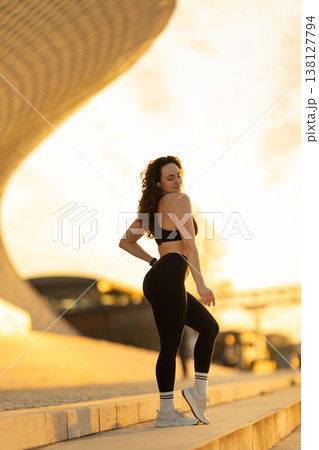 Woman posing in sportswear on city street at sunset 138127794