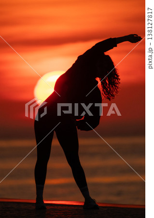 Woman silhouette stretching during vibrant red sunset Woman silhouette stretching during vibrant red sunset 138127817
