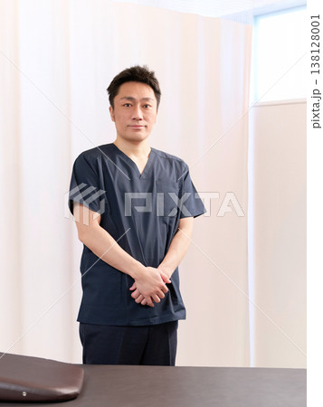 整体院の施術室に立つ男性整体師 整体院の施術室に立つ男性整体師 138128001