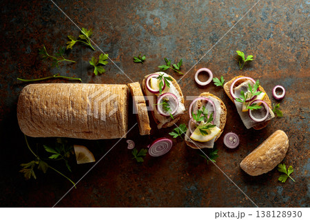Open sandwiches with herring filet, red onion, lemon, and parsley. 138128930