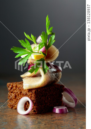 Rye bread canape with herring filet, red onion, lemon, and parsley. 138128937
