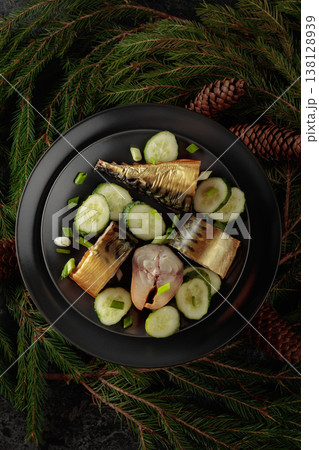 Smoked mackerel with fresh cucumber and green onions on a black plate. Smoked mackerel with fresh cucumber and green onions on a black plate. 138128939