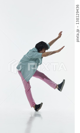 Man slipping with raised legs and arms trying to keep balance in studio isolated on white background. Man slipping with raised legs and arms trying to keep balance in studio isolated on white background. 138129436