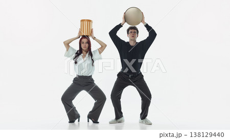 Man and woman balancing containers on head while standing in studio. 138129440
