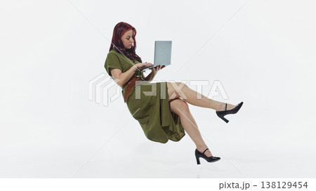 Woman floating while using laptop isolated on white background minimal studio shot. Woman floating while using laptop isolated on white background minimal studio shot. 138129454