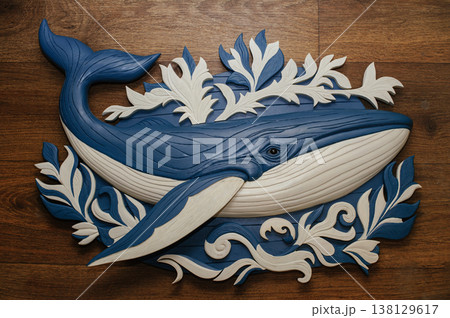Large carved wooden blue whale sculpture decorated with white leaf ornaments, displayed on a wooden surface. Large carved wooden blue whale sculpture decorated with white leaf ornaments, displayed on a wooden surface. 138129617