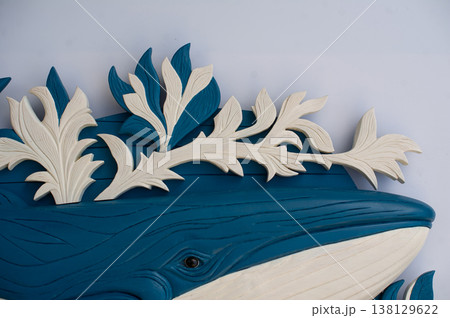 Close-up of intricate white floral relief ornaments and leaf details on a blue carved wooden whale sculpture Close-up of intricate white floral relief ornaments and leaf details on a blue carved wooden whale sculpture 138129622