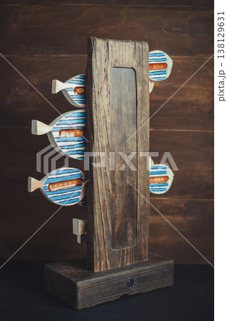 Rear view of a handmade wooden table lamp showing LED elements embedded in decorative fish on a rustic timber base. 138129631