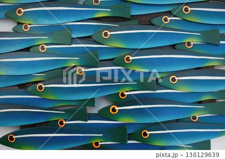 Macro shot of a school of stylized wooden fish with vibrant turquoise, blue, and yellow gradients on a white background. Macro shot of a school of stylized wooden fish with vibrant turquoise, blue, and yellow gradients on a white background. 138129639