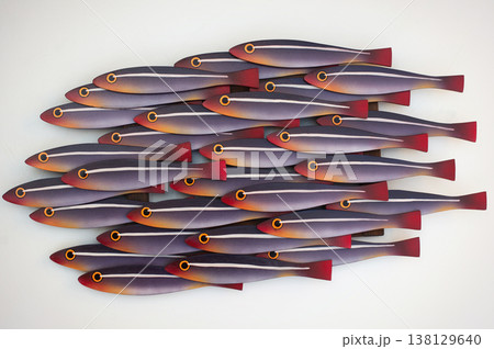 Artistic wooden wall panel featuring a school of stylized fish with purple, orange, and red gradient tones on a white background. Artistic wooden wall panel featuring a school of stylized fish with purple, orange, and red gradient tones on a white background. 138129640