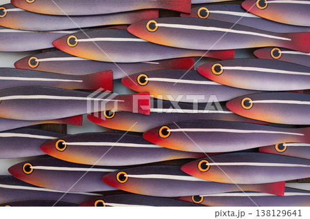 Macro photography of a wooden wall art panel showing a school of stylized fish with purple, orange, and red gradients. Macro photography of a wooden wall art panel showing a school of stylized fish with purple, orange, and red gradients. 138129641