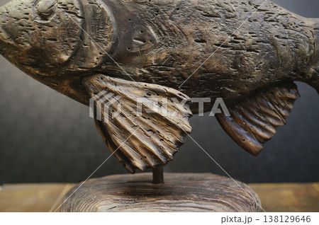 Macro photography focusing on the middle section of a hand-carved wooden fish, showcasing detailed weathered textures and grain on the fins and body. Macro photography focusing on the middle section of a hand-carved wooden fish, showcasing detailed weathered textures and grain on the fins and body. 138129646