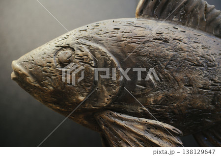Macro shot of a hand-carved wooden fish sculpture with aged, weathered texture and detailed wood grain. 138129647