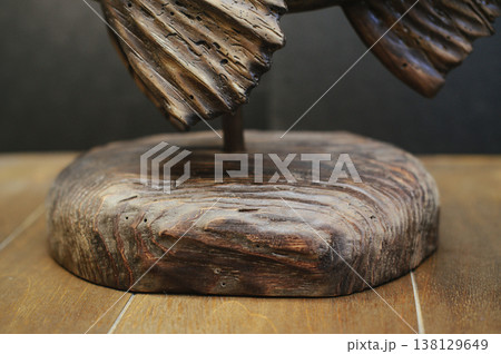 Macro shot of the solid timber base of a hand-carved fish sculpture, showcasing deep wood grain and weathered textures. 138129649