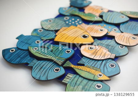 Perspective close-up of colorful stylized wooden fish on a blue base, highlighting the layered composition of the 3D wall art. Perspective close-up of colorful stylized wooden fish on a blue base, highlighting the layered composition of the 3D wall art. 138129655