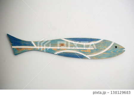 High-angle frontal view of an elongated decorative wooden fish with a distressed turquoise body, blue tail, and white stripe inlays on a light gray background. 138129683