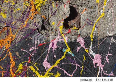 Vibrant paint splatter across rough concrete wall 138130336