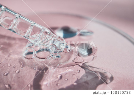 Pipette drawing clear liquid creating bubbles on pink surface Pipette drawing clear liquid creating bubbles on pink surface 138130758