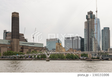 The monolithic brick chimney of the Tate Modern stands in industrial defiance against the sleek, modern glass of the Bankside skyline, while the delicate, shimmering thread of the Millennium Bridge The monolithic brick chimney of the Tate Modern stands in industrial defiance against the sleek, modern glass of the Bankside skyline, while the delicate, shimmering thread of the Millennium Bridge 138131006