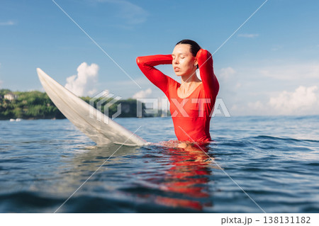 Surfer woman on surfboard in ocean. Surfer woman in water on sunny day Surfer woman on surfboard in ocean. Surfer woman in water on sunny day 138131182