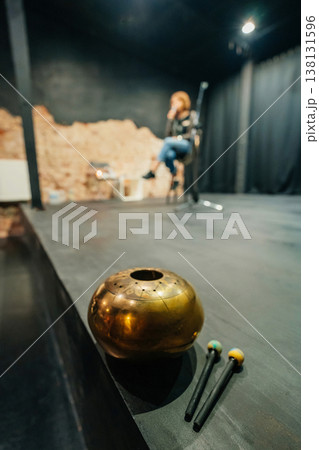 Musician Blurred On Empty Stage, Brass Bowl And Mallets In Foreground, Performer Tuning Instrument . 138131596