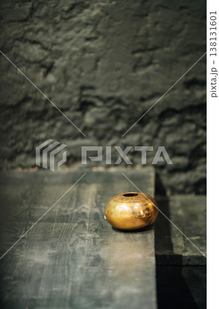 Brass Bowl On Dark Table, Weathered Stone Wall Backdrop, Soft Shadows, Warm Patina, Tranquil Mood . 138131601